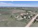 Expansive aerial view of a rural property, with fields, outbuildings, and distant mountain views on a sunny day at 2091 Tate Ave, Fort Lupton, CO 80621
