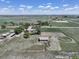 Aerial view of a farm property featuring a home, outbuildings, a horse pen, and pastures at 2091 Tate Ave, Fort Lupton, CO 80621