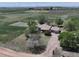 Aerial view showcasing a ranch-style house with a long drive and horse pastures at 2091 Tate Ave, Fort Lupton, CO 80621