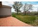 Brick patio leads to the grassy backyard, offering a serene outdoor space with mature trees and wooden fencing at 2091 Tate Ave, Fort Lupton, CO 80621