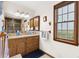 Bathroom featuring wood cabinetry, double sinks, and natural light at 2091 Tate Ave, Fort Lupton, CO 80621