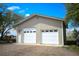 The large, detached garage has two bays with white doors and a side entrance door, set against a gravel driveway at 2091 Tate Ave, Fort Lupton, CO 80621