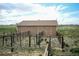 A low building with a fenced enclosure, set in a grassy field under a sky with scattered clouds at 2091 Tate Ave, Fort Lupton, CO 80621