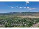 Wide aerial view showcasing a charming neighborhood nestled at the foot of majestic mountains under a bright, partly cloudy sky at 14191 W Amherst Ave, Lakewood, CO 80228