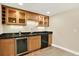 Convenient basement wet bar with modern cabinets, a sink, mini fridge and black countertop at 14191 W Amherst Ave, Lakewood, CO 80228
