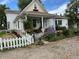 Charming home with a welcoming front porch, adorned with flowers, landscaping and a white picket fence at 8501 W 52Nd Ave, Arvada, CO 80002