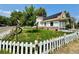 Landscaped front yard with a white picket fence, green lawn, and ornamental features at 8501 W 52Nd Ave, Arvada, CO 80002