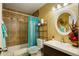 Bathroom featuring brown tiled shower/bath, single sink vanity, and matching circular mirror at 10150 E Virginia Ave # 18-302, Denver, CO 80247
