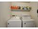 Bright laundry room features washer and dryer with storage shelf and cleaning supplies at 10150 E Virginia Ave # 18-302, Denver, CO 80247