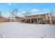 Spacious backyard with covered patio, outdoor seating, a storage shed and stairs to the upper level amid a snowy landscape at 2963 S Ivan Way, Denver, CO 80227