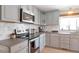 Close-up of a modern kitchen with stainless steel appliances, gray cabinets, and herringbone backsplash at 2963 S Ivan Way, Denver, CO 80227