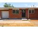 Charming brick home featuring a new black front door with a wreath, and a one-car garage at 5993 Oneida St, Commerce City, CO 80022