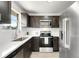 Modern kitchen featuring stainless steel appliances, dark cabinets, and white countertops at 5993 Oneida St, Commerce City, CO 80022