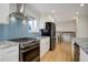 Modern kitchen with stainless steel appliances, stylish backsplash, and hardwood floors at 4410 S Estes St, Littleton, CO 80123