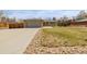A single-story home with a concrete driveway, rock-lined landscaping, and a lush green lawn at 396 Tucson St, Aurora, CO 80011
