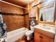 Traditional bathroom featuring a tub with tiled walls, wooden cabinets, and a decorative mirror at 13782 E Lehigh Ave # H, Aurora, CO 80014