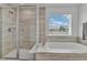 Bathroom view showcasing a glass-enclosed shower and a separate soaking tub with modern finishes at 6591 N Ceylon St, Denver, CO 80249