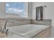 Close up of a luxurious soaking tub with stylish fixtures and neutral tile surround at 6591 N Ceylon St, Denver, CO 80249