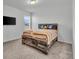 Bright bedroom featuring a uniquely designed wood bed frame and matching headboard with cool-toned walls and carpet at 6591 N Ceylon St, Denver, CO 80249