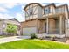 Inviting two-story home with a stone and siding facade, a two-car garage, and a well-maintained lawn with flowerbeds at 6591 N Ceylon St, Denver, CO 80249