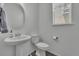 Neutral powder room with pedestal sink, toilet, and decorative mirror at 6591 N Ceylon St, Denver, CO 80249