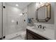 Modern bathroom featuring a glass shower, sleek vanity with stone countertop, and decorative mirror at 7912 Raphael Ln, Littleton, CO 80125