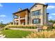 Stately stone home exterior featuring a covered deck, large windows, and lush landscaping at 7912 Raphael Ln, Littleton, CO 80125