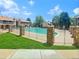 Community pool surrounded by a fence with brick pillars and green lawn area at 8225 Fairmount Dr # 106, Denver, CO 80247