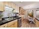 Modern kitchen area with stainless steel appliances, sleek granite counters, and natural wood cabinetry and dining area at 8225 Fairmount Dr # 106, Denver, CO 80247
