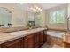 A bathroom with a large mirror, double sinks, tub and natural light from a large window at 10064 Bluffmont Ct, Lone Tree, CO 80124