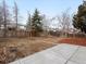 A spacious backyard with a concrete patio, garden beds, wood fence, and mature trees creating a private outdoor space at 1643 S Fairplay St, Aurora, CO 80012