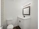 A white bathroom features a single sink vanity with modern black fixtures, a framed mirror and subway tile in the shower at 1643 S Fairplay St, Aurora, CO 80012