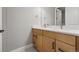 Bathroom featuring double sinks with wood cabinets, gray flooring, and a large mirror at 3370 Backdrop Ct, Castle Rock, CO 80108