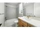 Bright bathroom with a gray tiled shower/tub, wood vanity, and white countertop sink at 3370 Backdrop Ct, Castle Rock, CO 80108