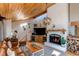 Comfortable living room with vaulted wood ceiling, cozy fireplace, and an entertainment center next to the stairway at 8277 Carriage Ln, Parker, CO 80134