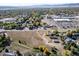 Expansive aerial view of the property showcasing its location near commercial areas, trees, and distant mountain views at 6365 W Coal Mine Ave, Littleton, CO 80123