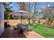 Backyard features wooden deck, dining table and chairs, shade umbrella, and grassy yard at 15357 Flowergate Way, Parker, CO 80134