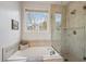 Modern bathroom featuring a soaking tub with window and a separate glass shower at 15357 Flowergate Way, Parker, CO 80134