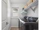 Clean laundry room with modern washer and dryer, storage shelves, and a bright window at 15357 Flowergate Way, Parker, CO 80134