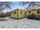 View of the backyard with yellow siding on the house in a snowy setting at 3052 S Joplin Ct, Aurora, CO 80013