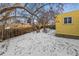 Backyard view showing the yellow house siding and a wooden fence with snow on the ground at 3052 S Joplin Ct, Aurora, CO 80013