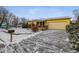 Front exterior view of the yellow house with a snow-covered yard and a driveway at 3052 S Joplin Ct, Aurora, CO 80013