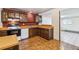 Functional kitchen with brick wall accent, wooden cabinets, white appliances, and view of a bright dining area at 3052 S Joplin Ct, Aurora, CO 80013