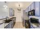 Galley kitchen showcasing blue cabinets, granite countertops, and stainless steel appliances at 9180 Rolling Way # 303, Parker, CO 80134