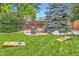 Beautiful backyard with green grass, mature trees, and a cornhole game at 7573 S Saulsbury Ct, Littleton, CO 80128