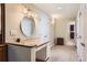 Hallway bathroom with a granite topped makeup vanity and round mirror at 7573 S Saulsbury Ct, Littleton, CO 80128