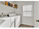 A bright laundry room with shelving for storage, a window and a washer and dryer ready for use at 13464 E 107Th Ave, Commerce City, CO 80022