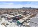 City skyline view from a residential neighborhood with snow-covered houses, fences, and tree branches at 1864 W 41St Ave, Denver, CO 80211