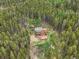 An aerial shot shows a cabin nestled in the woods surrounded by a ring of tall, dense trees at 509 Paiute Rd, Evergreen, CO 80439