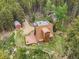 An aerial view shows the house with a barn behind it and trees surrounding the entire property at 509 Paiute Rd, Evergreen, CO 80439
